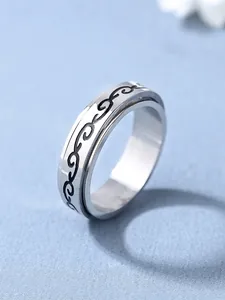 Gros plan d'une bague rotative en acier argenté avec des motifs de vagues noires gravés