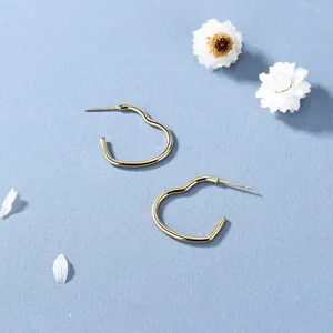 Gepolijste gouden hartvormige oorringen op blauwe achtergrond met decoratieve bloemen