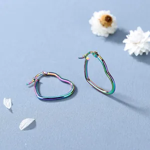 Irillerende hartvormige oorringen met regenboogafwerking op een lichtblauwe ondergrond