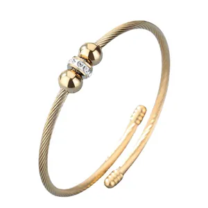 Bracelet jonc ouvert torsadé en acier titane doré avec perles de chance et zircone
