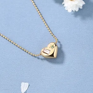 Gouden hartketting met roze kristal en groene stersteen aan een fijne kralenketting