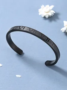 Dettaglio bracciale rigido nero con numeri romani su superficie azzurra strutturata