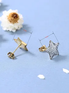 Détail de boucles d'oreilles étoile de 1 cm avec base dorée et paillettes argentées