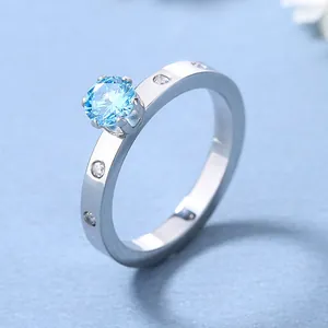 Détail d'une bague en acier titane sertie d'une pierre bleu clair avec quatre griffes
