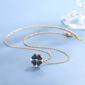 Collana a quadrifoglio dorata con cristalli a cuore blu su sfondo blu decorativo