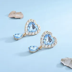 Dettaglio macro di orecchini a cuore in cristallo azzurro con finitura in strass