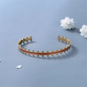Adjustable golden open bangle with red enamel inlay and geometric textured edge details