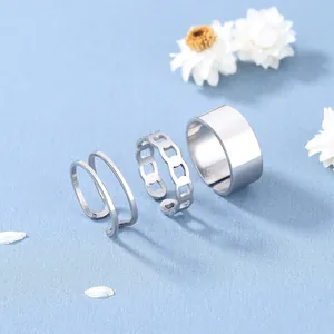 Dettaglio di tre anelli regolabili in argento con catena geometrica e superficie lucida