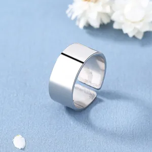 Primo piano di un anello largo in argento con finitura lucida a specchio su sfondo azzurro