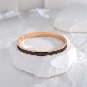 Βραχιόλι από τιτάνιο με επιχρύσωση 18K και μαύρο σμάλτο σε λευκή πέτρινη επιφάνεια