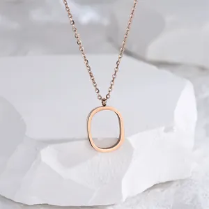 Collier minimaliste en or rose avec pendentif évidé en forme de O sur fond pierre