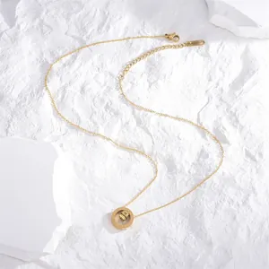 Collana dorata con numeri romani e pendente a cubo con cristalli su sfondo in pietra