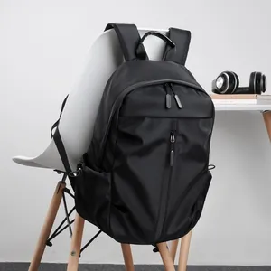 Minimalist black USB business backpack for laptops with waterproof fabric on a chair