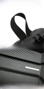 Detail of men's polyhedral hardshell crossbody bag with carbon fiber texture and handle
