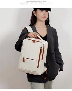 Detail view of cream travel backpack with brown trim and integrated USB charging port