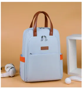 Detail view of light blue nylon backpack featuring brown top handle and orange side pockets