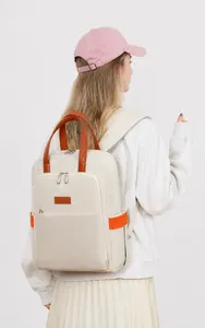 Detail of off-white canvas backpack with brown leather handle and orange side ribbon accents