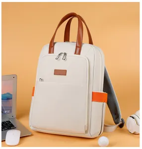 Detail view of a beige travel backpack with leather handles and orange accents for laptop