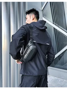 Detailed view of black hard shell crossbody bag with carbon fiber texture and adjustable strap