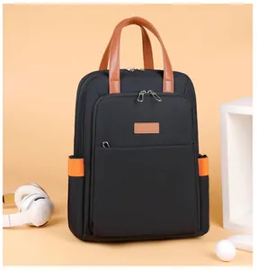 Detail of a casual black backpack with brown leather handles and orange side webbing