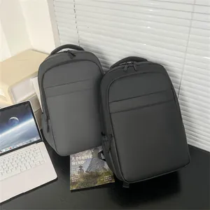 Modern waterproof business backpacks in grey and black next to laptop for tech commute