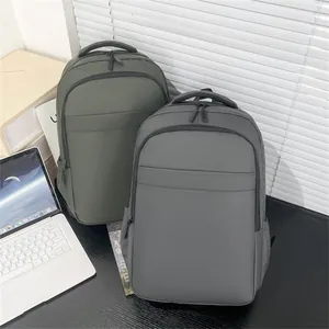 Waterproof laptop backpack shown in dark gray and olive green on an office desk