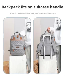 Gray diaper backpack with brown leather trim showing suitcase luggage strap attachment