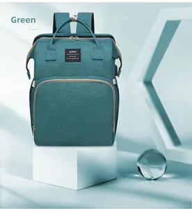 Primer plano de bolsa de pañales multifuncional verde en plataforma blanca con luz suave