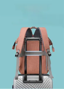 Detail of the back luggage strap on a coral orange diaper backpack for easy travel