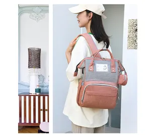 Close-up of a large capacity diaper backpack in grey and pink with side pockets