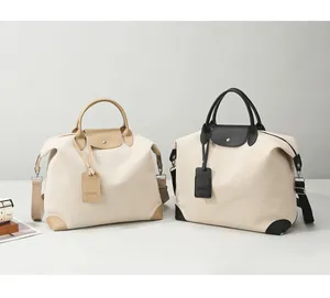 Detail of canvas travel bags with leather trim, featuring luggage tags and shoulder straps