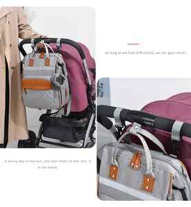 Detail showing multifunctional grey baby diaper bag with leather trim hanging on stroller hooks