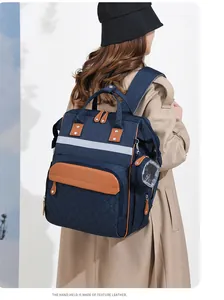 Detail of navy multi-functional baby bag with leather handles and reflective safety strip