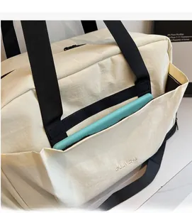 Vue détaillée de la grande poche frontale d'un sac de sport beige avec une tablette
