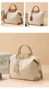 Macro detail of beige canvas travel bag featuring brown leather handles and brand tag