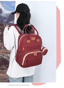 Close-up of wine red diaper backpack with leather details and matching mini pouch