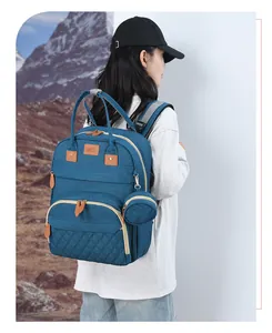 Blue canvas diaper backpack with quilted front pocket and round accessory pouch