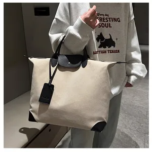 Detail of canvas travel tote with black leather handles and NOCC brand tag on side