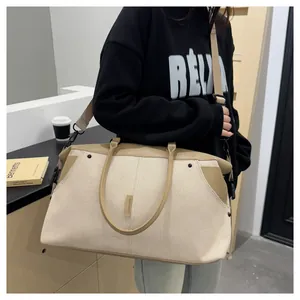 Close-up of the beige canvas travel bag featuring brown leather trim and shoulder strap