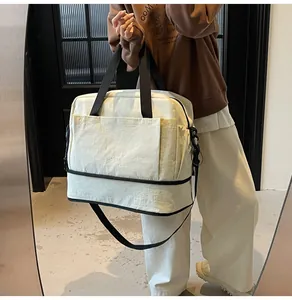 Détail d'un sac de sport beige avec compartiment à chaussures séparé et bandoulière réglable