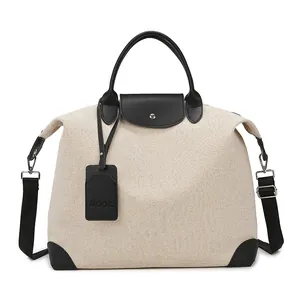 Large beige canvas travel bag with black leather handles and detachable shoulder strap