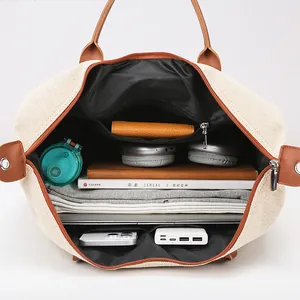 Large travel bag in off-white canvas with leather handles and organized inner pockets