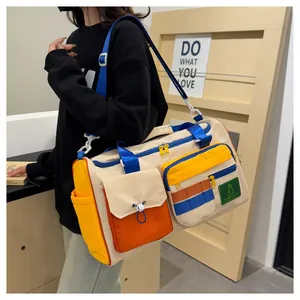 Detail of color-block travel bag with front utility pockets and adjustable blue strap