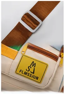 Detail of adjustable shoulder strap and leather logo patch on contrast travel duffel bag