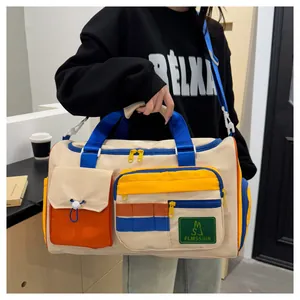 Detail view of large travel bag with contrast pockets, beige fabric, and orange flap