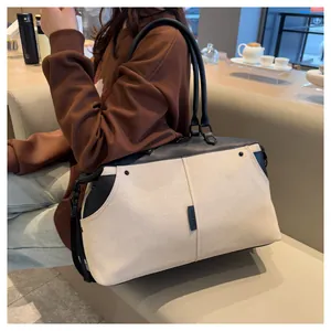 Detail showing high-quality off-white canvas and black leather handles of the travel bag
