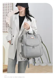Detailed view of grey diaper bag with multiple pockets worn by a female model