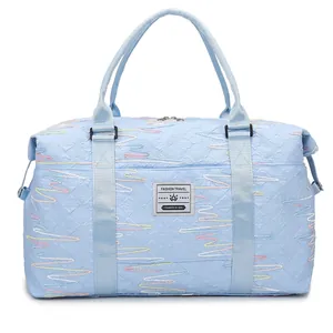Light blue quilted travel duffel bag with colorful embroidery and top handles