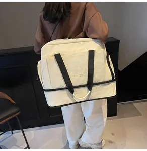 Détail macro du sac de voyage de fitness étanche montrant le tissu beige et la broderie