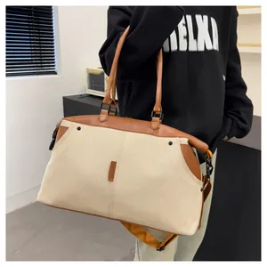 Detail of canvas travel bag with leather handles and metallic hook on a model's shoulder